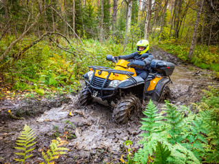 ATV rides through the mud. Off-road adventures. A man manages ATV on the road. All-terrain vehicle. Quad drives through the swamp