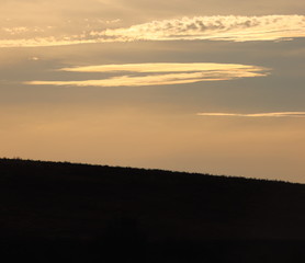 sunset in mountains, silhouetted landscape of hill in shade over vibrant sunset, silhouetted hill with orange sunset over, bright sunset clouds, sunset over hillside,