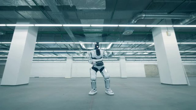 Cyborg is dancing in an empty warehouse room