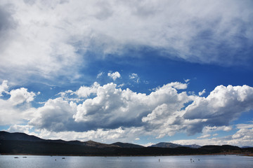 Fototapeta premium clouds over lake with people and mountains
