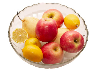 apples, pears, lemons in a transparent glass plate on a light background
