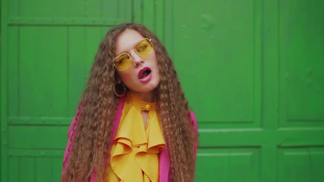Young fashionable woman chewing bubble gum, blowing bubblegum bubbles