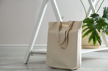 Eco bag and houseplant near white wall indoors. Space for design