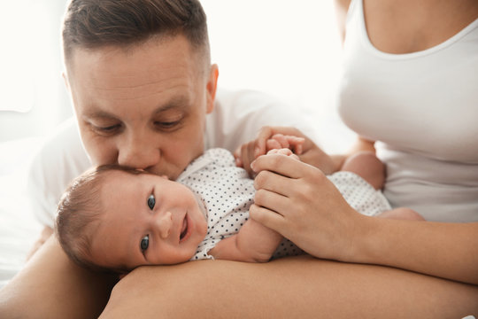 Happy couple with their newborn baby on light background