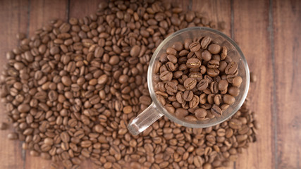 Coffee cup filled with coffee beans over a brown background