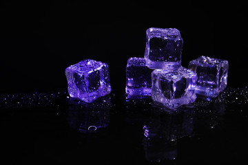 Pile of crystal clear ice cubes on black background