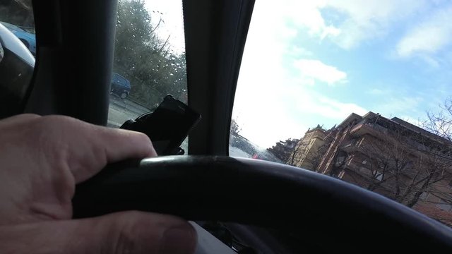 A man drive a car on city road with traffic. Point of View from stearing wheel