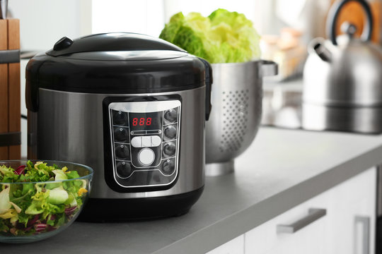 Modern electric multi cooker and food on kitchen countertop. Space for text