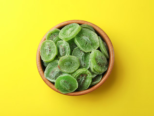 Fototapeta premium Bowl with slices of kiwi on color background, top view. Dried fruit as healthy food