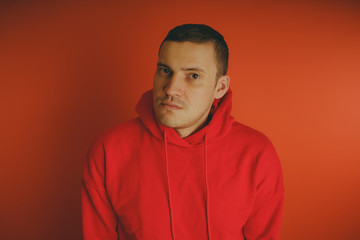 Fototapeta premium Crazy and charismatic guy posing on an orange background. A man in a red tracksuit.