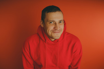 Obraz premium Crazy and charismatic guy posing on an orange background. A man in a red tracksuit.