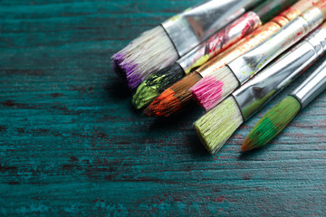 Fototapeta premium Different paint brushes on wooden table, closeup. Space for text