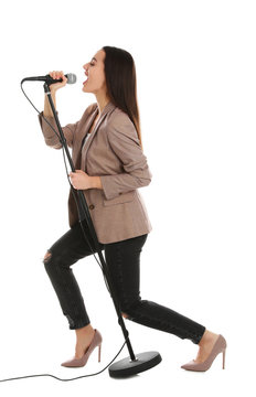 Young stylish woman singing in microphone on white background