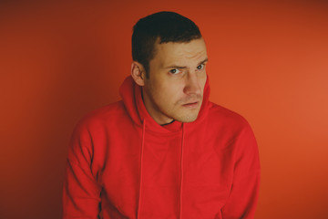 Obraz premium Crazy and charismatic guy posing on an orange background. A man in a red tracksuit.
