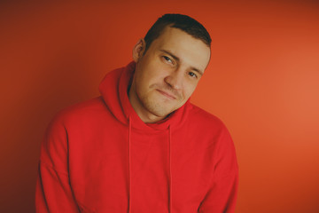 Crazy and charismatic guy posing on an orange background. A man in a red tracksuit.