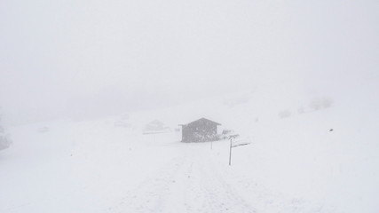 Fototapeta na wymiar Wooden hut in a winter mountain landscape with falling snow.
