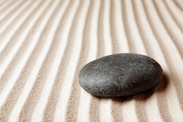 Fototapeta na wymiar Zen garden stone on sand with pattern, space for text. Meditation and harmony