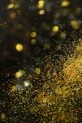 Shiny golden glitter on blurred background with bokeh effect. Space for text