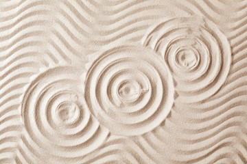 Fototapeta na wymiar Zen garden pattern on sand as background, top view. Meditation and harmony