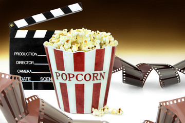 Popcorn, movie clapper  and film strips. Cinema concept image
