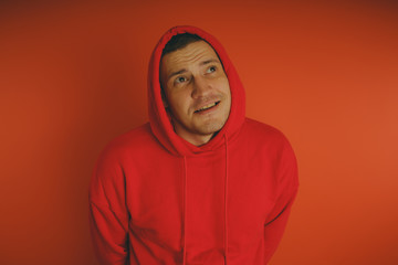 Fototapeta premium Crazy and charismatic guy posing on an orange background. A man in a red tracksuit.