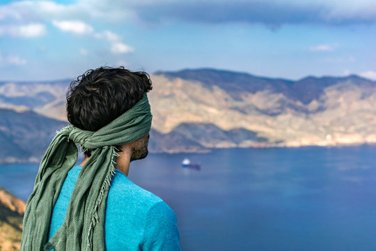 Caucasian young man with blindfolder on eyes at the top of a cliff over seascape and landscape