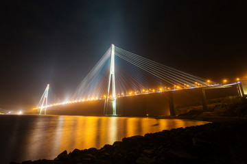 Obraz premium Amazing zooming out aerial view of the Russky Bridge, the world's longest cable-stayed bridge, and the Russky (Russian) Island in Peter the Great Gulf in the Sea of Japan. Sunrise. Vladivostok, Russia