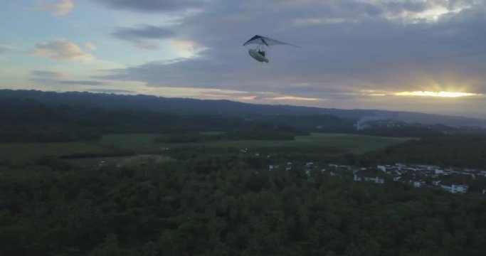 FIB - Flying Inflatable Boat. Aerial shot looking at the amphibious aircraft flying in the sky above the island and the sea at sunset
