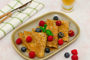 Crepes with berries. Crepes with raspberry, blueberry and caramel sauce. Pancakes 