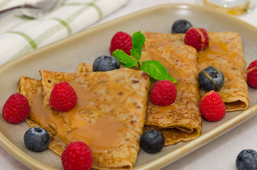 Crepes with berries. Crepes with raspberry, blueberry and caramel sauce. Pancakes 