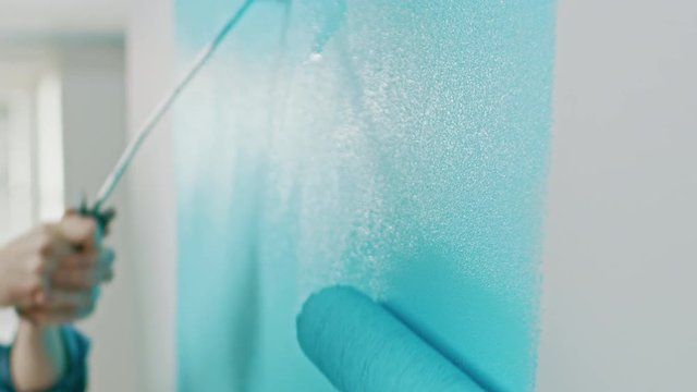 Close Up Shot of a Wall Being Painted with a Roller. Color of the Paint is Light Blue. Flat Renovations at Home.