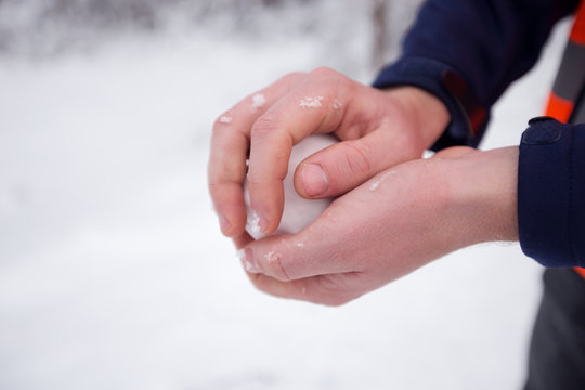 Hands holding fresh snow, man making snowball