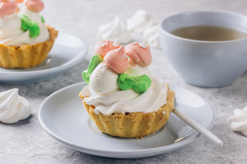 Delicious funny tartlets with meringue for kids on a light blue plate.