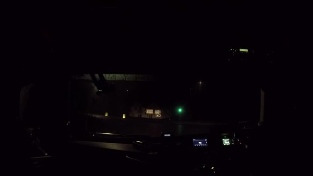 In Cab Shot Of HGV (truck) Driving Through A Set Of UK Traffic Lights At Night.