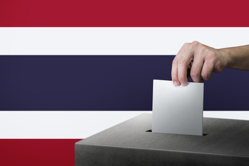Hand holding ballot paper for election vote at thailand national flag background. Thailand voting concept.