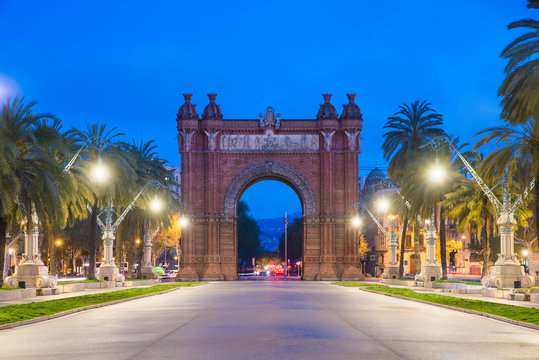 Bacelona Arc De Triomf At Night In The City Of Barcelona In Catalonia, Spain. The Arch Is Built In Reddish Brickwork In The Neo-Mudejar Style