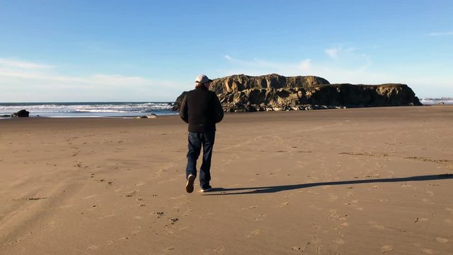 Lonely man walking on a beautiful beach in Bandon, Oregon during daytime