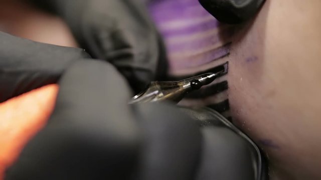 Tattoo artist paint over tattoo on skin of client, macro view on the needle