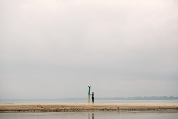 Female surfer with long board on the sea silhouette