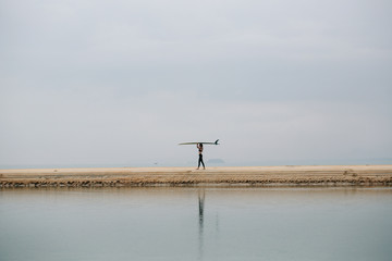 Female surfer with long board on the sea silhouette