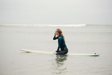 Female surfer seating on long board in the ocean