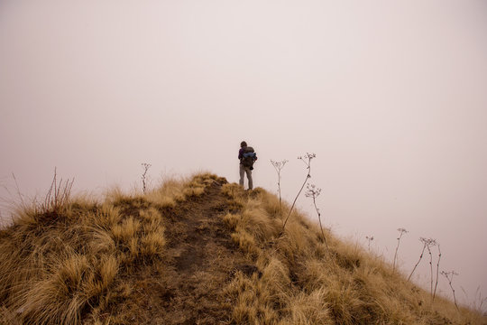 Traveller Hiker man lost and looking for the way in mist fog mountain top