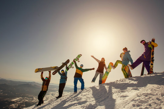 Group of happy friends having fun playing in snow. Ski and snowboard sunny holiday