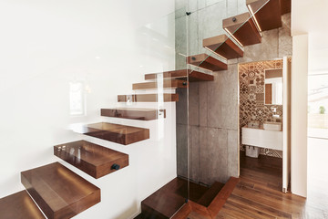 Stairs in living room with open door to bathroom and glass wall