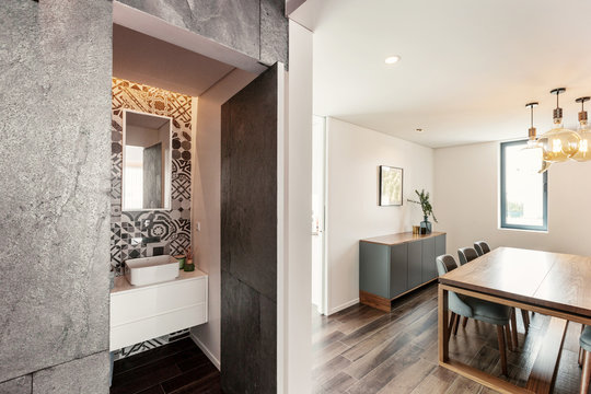 Open door from living room to bathroom. Modern interior, grey stone wall design