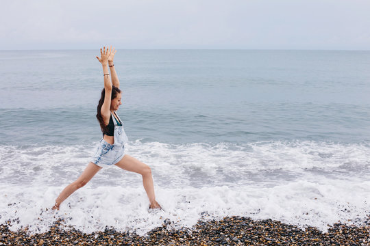 Laughing woman doing yoga exercise on sea shore