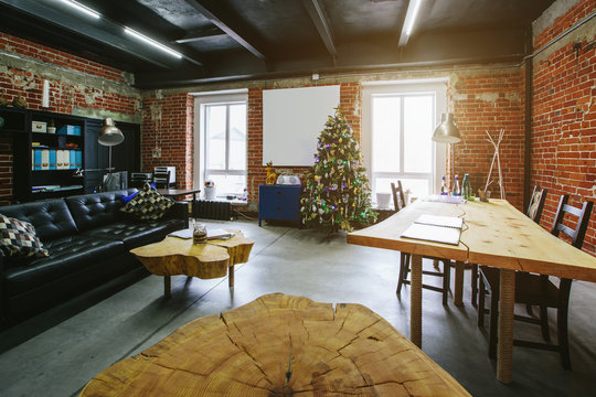 Christmas tree in modern Loft Office interior. Wooden decoration tables, red brick wall