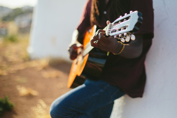 Portrait of musician African man  wearing dreadlocks playing guitar outdoor
