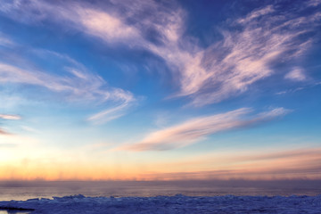 Naklejka na ściany i meble Winter blue sky and red sunrise at frozen lake with sea smoke