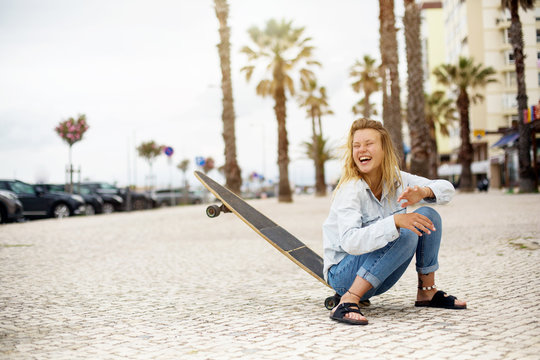 skateboarder girl smiling and have fan on street with palm trees